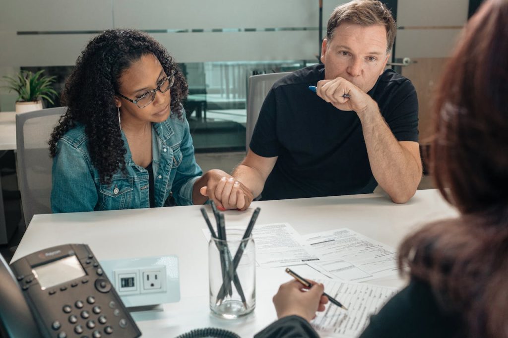 A couple discusses adoption process with an advisor in a modern office setting.